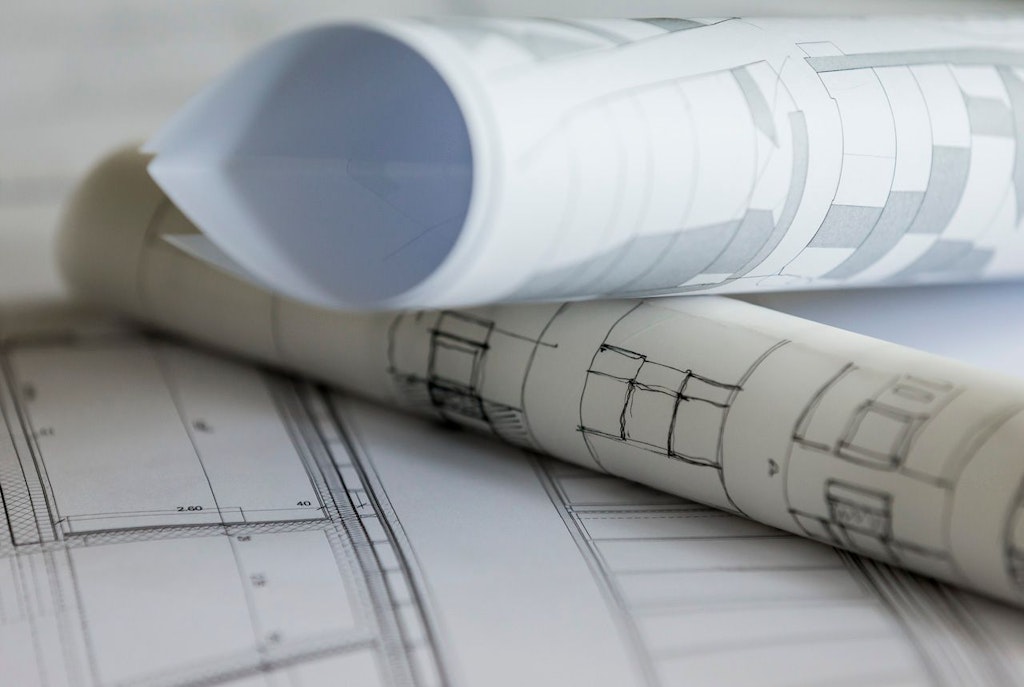 Plans d’architecte posés sur une surface de travail.