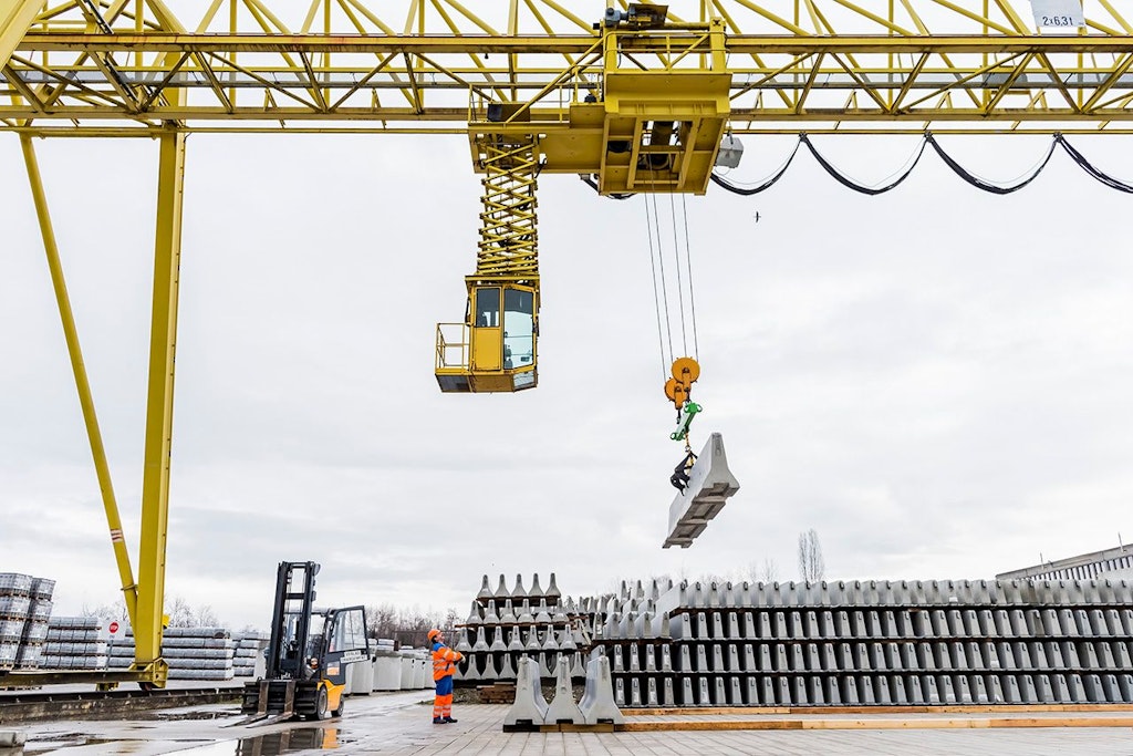 Stockage d’éléments en béton préfabriqués au moyen d’une grue industrielle.